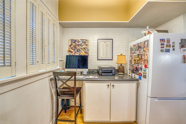 kitchen featuring white refrigerator, white cabinets, and dark stone countertops