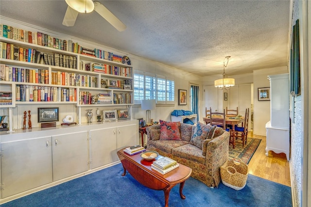 living area with a textured ceiling, light colored carpet, and ceiling fan with notable chandelier