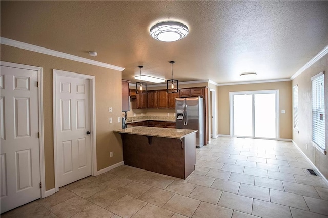 kitchen featuring decorative light fixtures, light tile flooring, light stone countertops, ornamental molding, and stainless steel refrigerator with ice dispenser