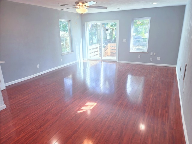 unfurnished room with ceiling fan, dark wood-type flooring, and a healthy amount of sunlight