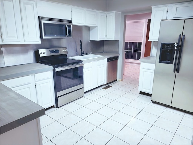 kitchen featuring light tile floors, stainless steel appliances, white cabinets, backsplash, and sink