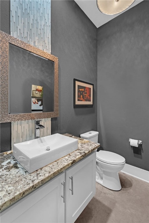 bathroom with concrete floors, vanity, and toilet