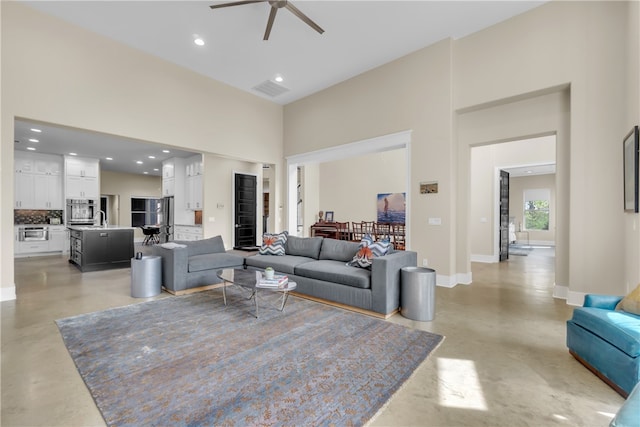 living room featuring ceiling fan and a high ceiling