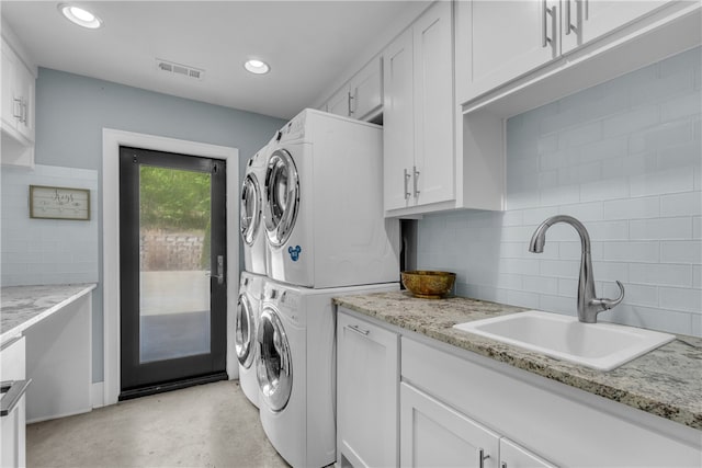 washroom with stacked washer / dryer, cabinets, and sink