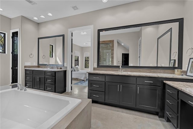 bathroom featuring a relaxing tiled bath, oversized vanity, and double sink