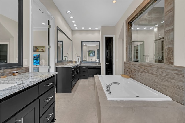 bathroom with backsplash, double sink vanity, tile floors, and tiled bath