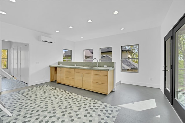 kitchen featuring light brown cabinetry, sink, a healthy amount of sunlight, and a wall mounted air conditioner