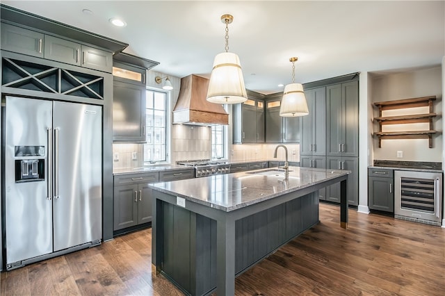 kitchen with high end refrigerator, wine cooler, tasteful backsplash, hanging light fixtures, and premium range hood