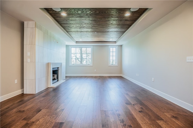 unfurnished living room with a fireplace, a raised ceiling, and dark wood-type flooring