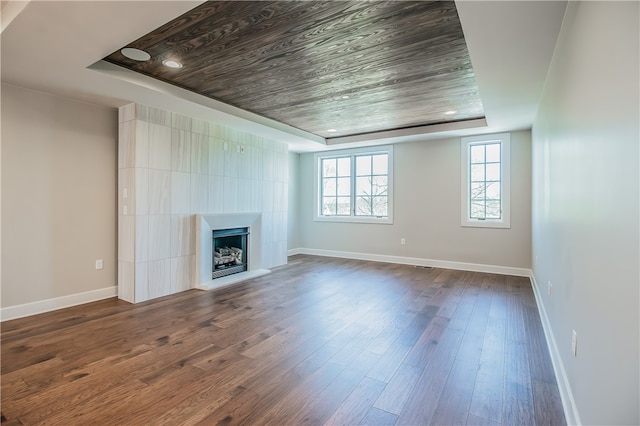 unfurnished living room with wooden ceiling, a raised ceiling, dark wood-type flooring, and tile walls