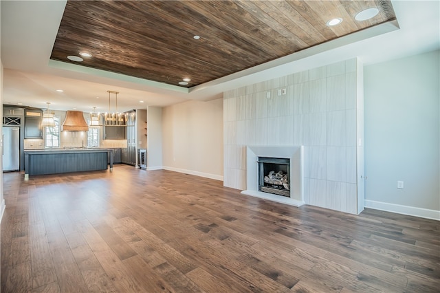 unfurnished living room featuring dark hardwood / wood-style flooring, a fireplace, wooden ceiling, and a tray ceiling