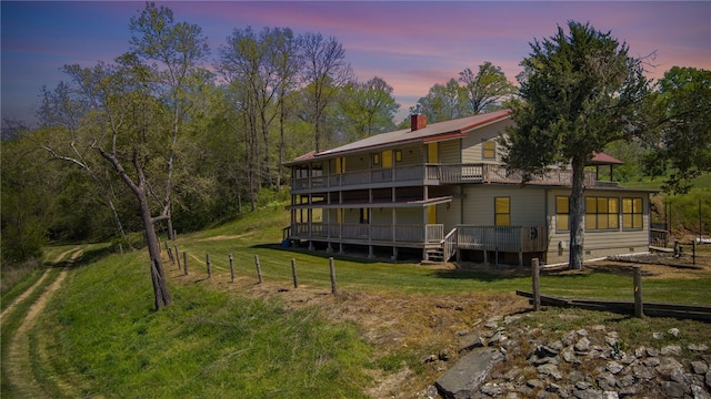 back house at dusk with a yard and a balcony