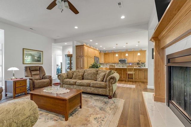 living room featuring sink, ceiling fan, and light wood-type flooring