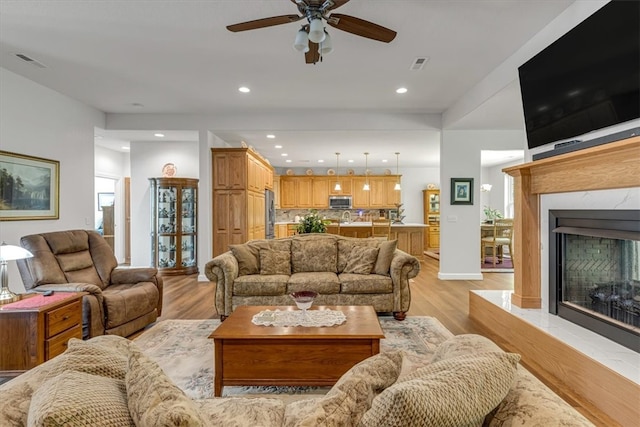 living room with a wealth of natural light, sink, ceiling fan, and light wood-type flooring