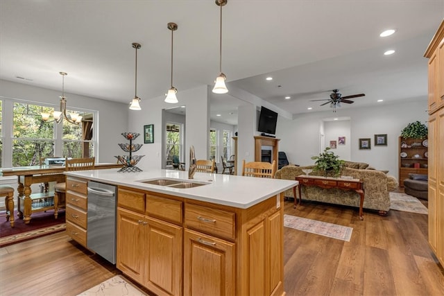 kitchen with sink, stainless steel dishwasher, decorative light fixtures, an island with sink, and hardwood / wood-style flooring