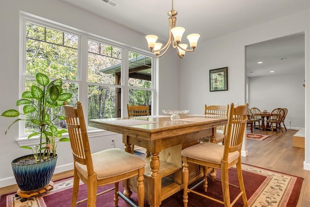 dining area featuring hardwood / wood-style floors and an inviting chandelier