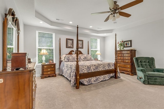 bedroom featuring light carpet, ceiling fan, and a raised ceiling