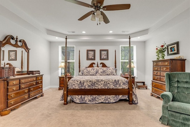 bedroom featuring a raised ceiling, ceiling fan, and light carpet