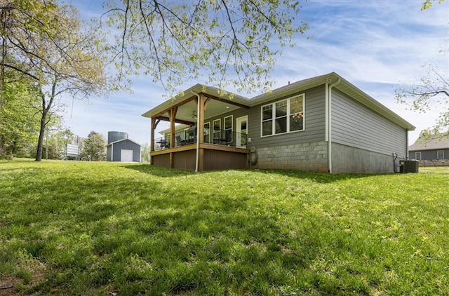 rear view of property featuring a yard and central AC unit