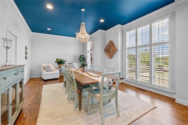 dining space featuring crown molding, dark hardwood / wood-style floors, and an inviting chandelier