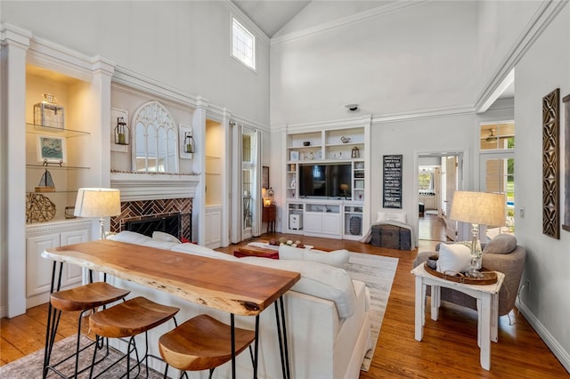 living room featuring hardwood / wood-style floors, built in features, and high vaulted ceiling