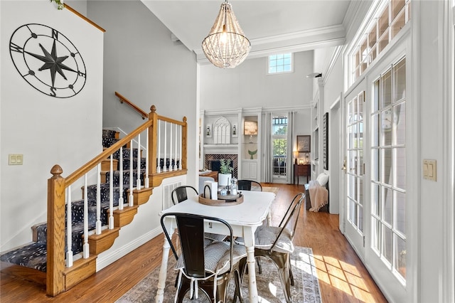 dining room with a notable chandelier, a high ceiling, crown molding, french doors, and light hardwood / wood-style flooring