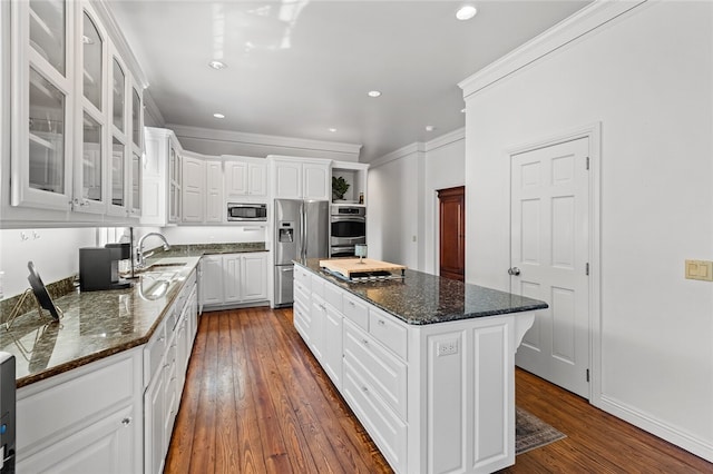 kitchen featuring white cabinets, dark hardwood / wood-style flooring, a center island, and appliances with stainless steel finishes