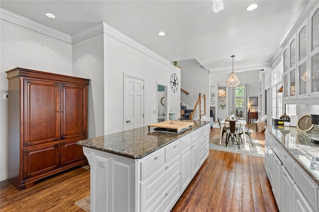 kitchen featuring a center island, crown molding, white cabinets, and hardwood / wood-style floors