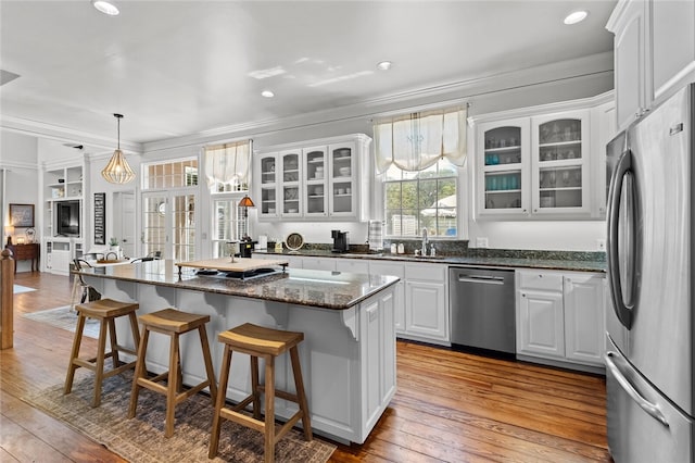 kitchen with a kitchen island, light hardwood / wood-style floors, white cabinetry, crown molding, and stainless steel appliances