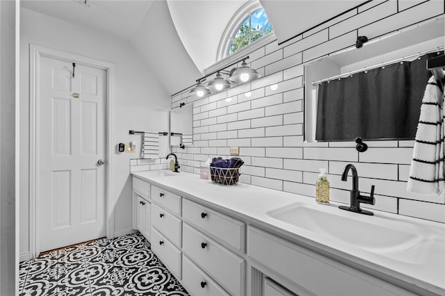 bathroom featuring vaulted ceiling, vanity, backsplash, and tile floors