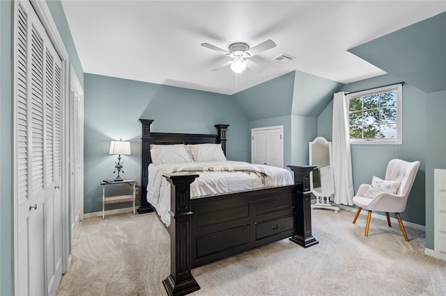 carpeted bedroom featuring vaulted ceiling, ceiling fan, and two closets