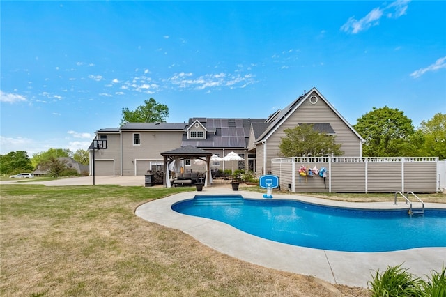 back of property featuring a patio area, a yard, solar panels, and a fenced in pool