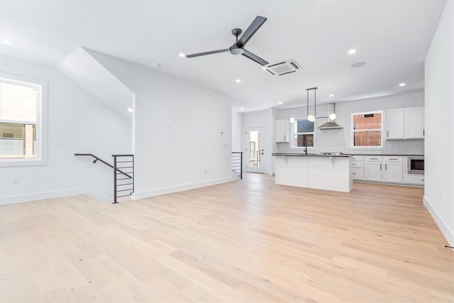 unfurnished living room with light hardwood / wood-style flooring, ceiling fan, and sink