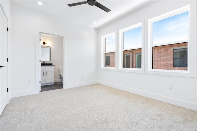 unfurnished bedroom with ensuite bath, ceiling fan, and carpet