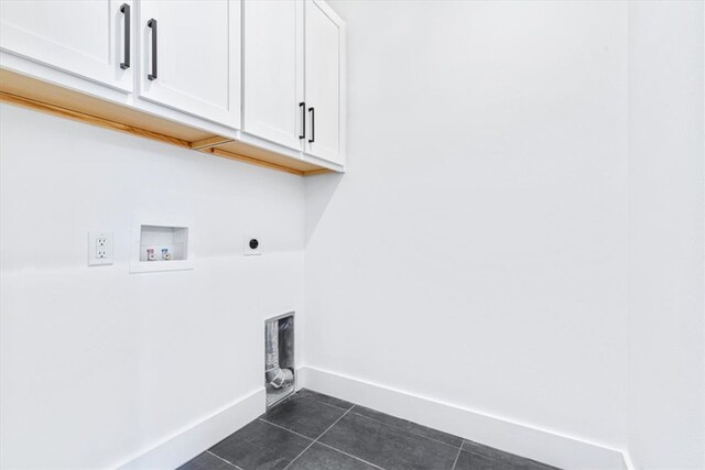 washroom featuring cabinets, hookup for an electric dryer, hookup for a washing machine, and dark tile floors