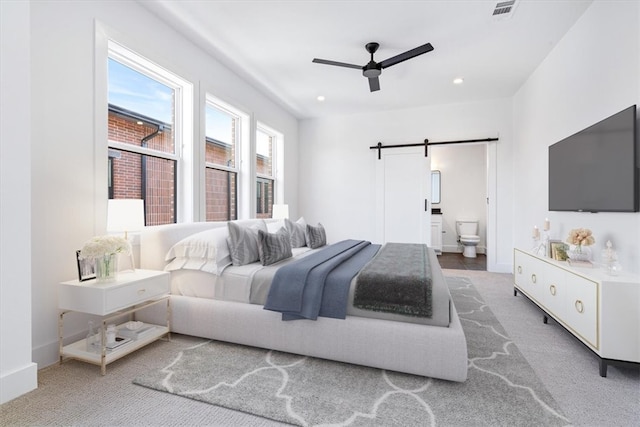 bedroom featuring carpet flooring, a barn door, ceiling fan, and ensuite bathroom