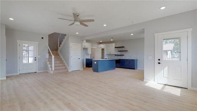 unfurnished living room featuring ceiling fan, sink, and light wood-type flooring