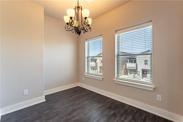 unfurnished room with a chandelier and dark hardwood / wood-style flooring