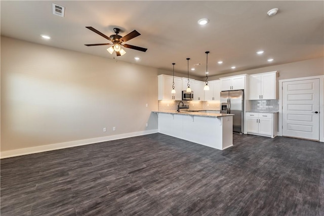 kitchen with hanging light fixtures, appliances with stainless steel finishes, white cabinets, and kitchen peninsula