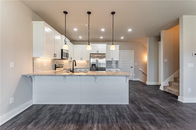 kitchen featuring pendant lighting, sink, appliances with stainless steel finishes, white cabinets, and kitchen peninsula