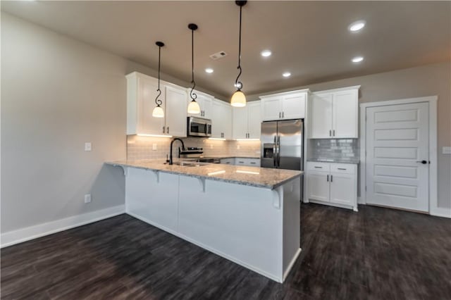 kitchen featuring stainless steel appliances, hanging light fixtures, white cabinets, and kitchen peninsula