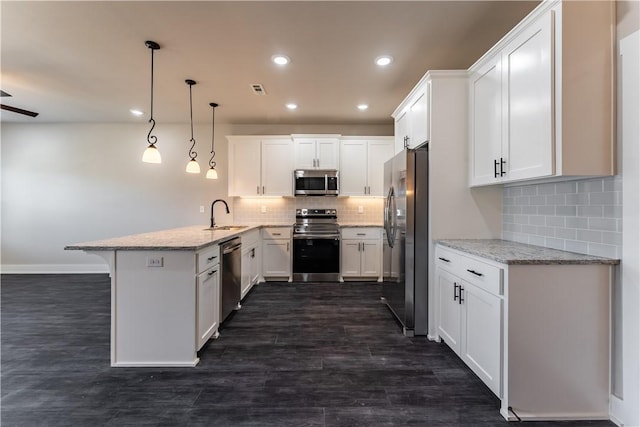 kitchen featuring pendant lighting, stainless steel appliances, kitchen peninsula, and white cabinets