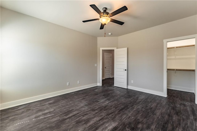 unfurnished bedroom with a closet, a walk in closet, dark hardwood / wood-style floors, and ceiling fan