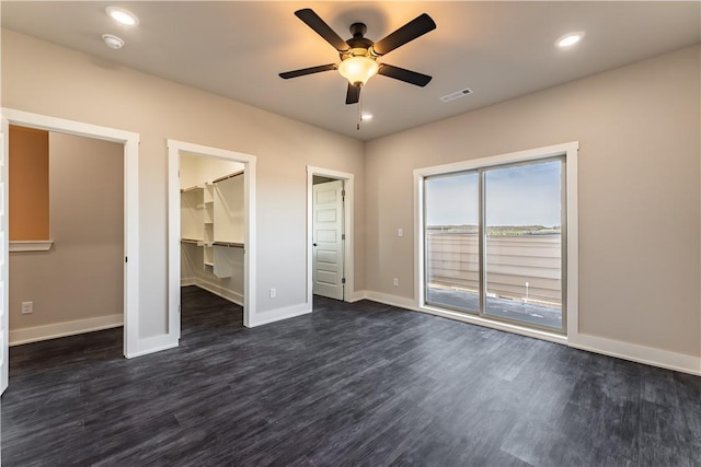 unfurnished bedroom with a walk in closet, dark hardwood / wood-style floors, access to exterior, and ceiling fan