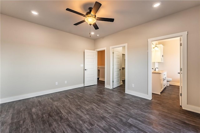 unfurnished bedroom with dark wood-type flooring, ceiling fan, ensuite bathroom, and a walk in closet