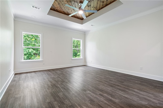 empty room with a tray ceiling, a wealth of natural light, ceiling fan, and dark hardwood / wood-style floors