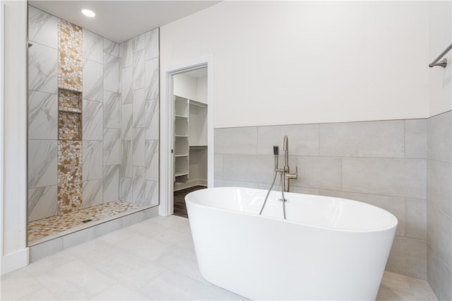 bathroom with plus walk in shower, tile patterned floors, and tile walls