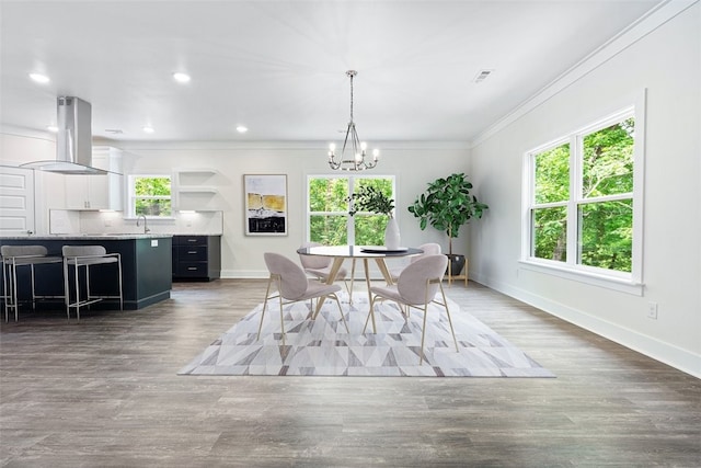 dining room with dark hardwood / wood-style floors, ornamental molding, sink, and a chandelier