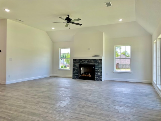 unfurnished living room with a wealth of natural light, a stone fireplace, and light wood-type flooring