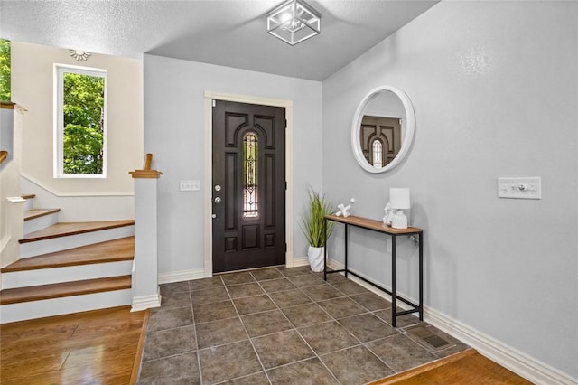 entrance foyer with dark tile patterned flooring and a textured ceiling